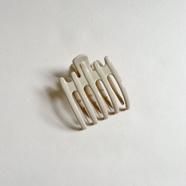 Shiny tan lay-flat hair claw on beige background.