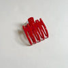 Shiny red lay-flat hair claw on beige background.