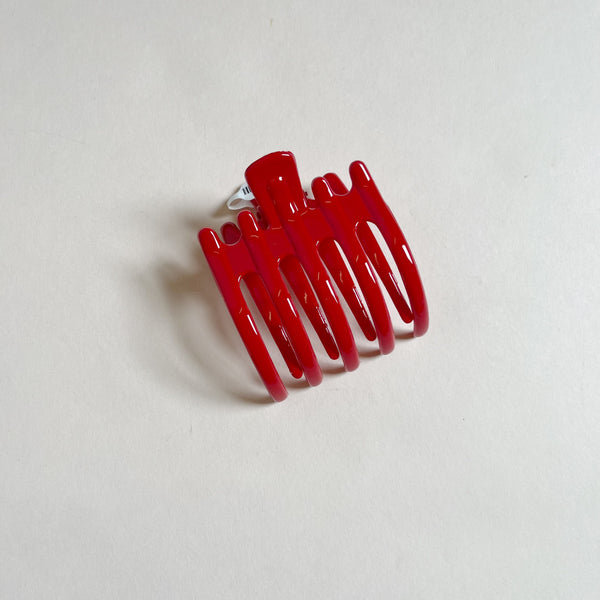 Shiny red lay-flat hair claw on beige background.