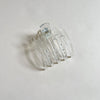 Clear lay-flat hair claw on beige background.