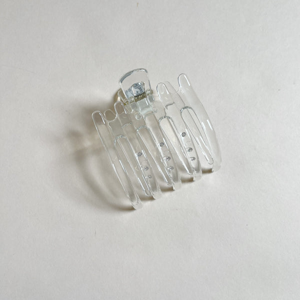 Clear lay-flat hair claw on beige background.