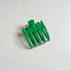 Shiny emerald green lay-flat hair claw on beige background.