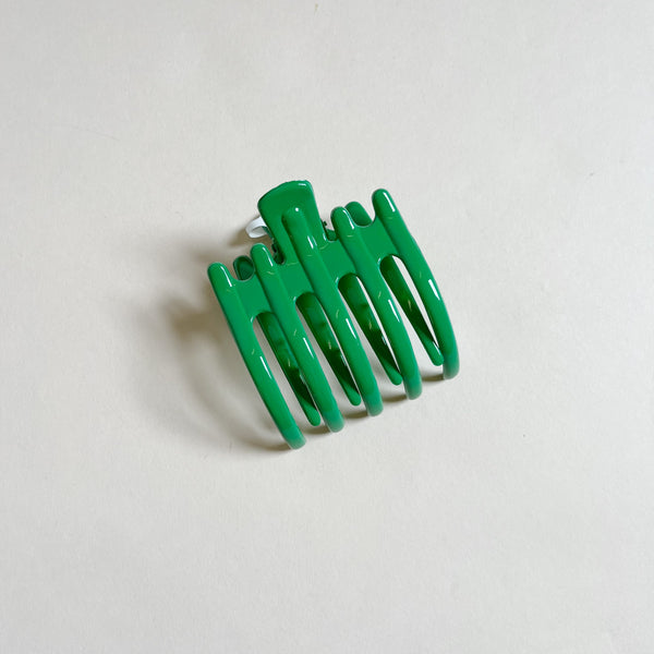 Shiny emerald green lay-flat hair claw on beige background.