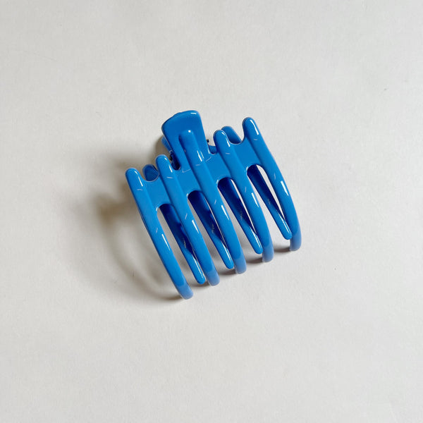 Shiny blue lay-flat hair claw on beige background.