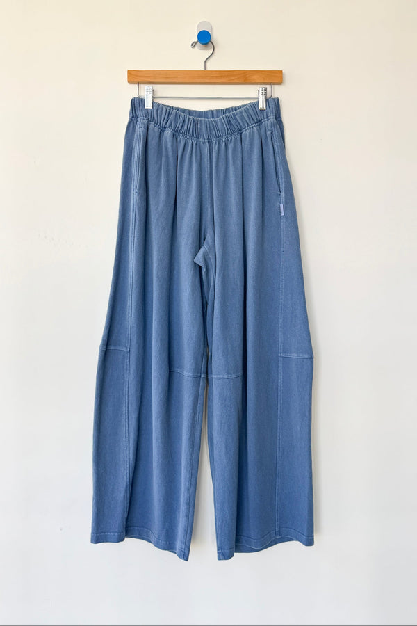 Blue pants hanging on a wooden hanger against a white background
