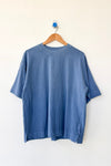 Blue t-shirt on a wooden hanger against a white background