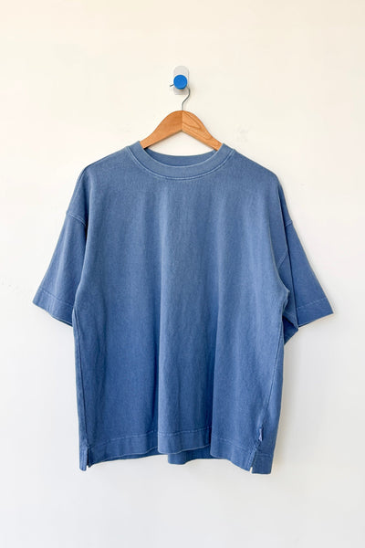 Blue t-shirt on a wooden hanger against a white background