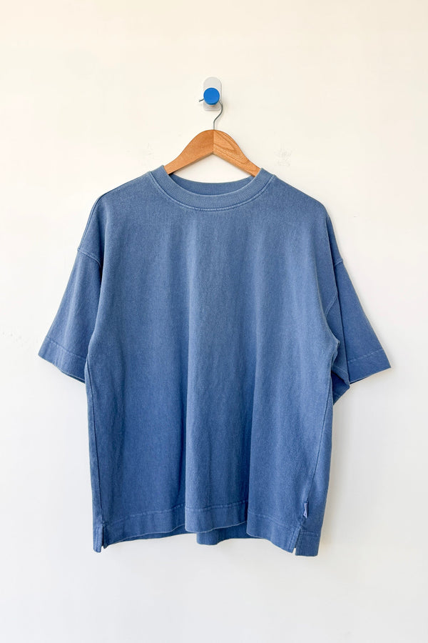 Blue t-shirt on a wooden hanger against a white background