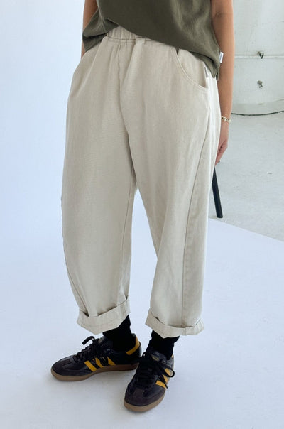 Person wearing beige cuffed pants with black sneakers and a green shirt.