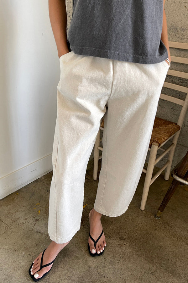 Person wearing beige pants with a grey shirt and black sandals.
