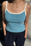 Person wearing a blue tank top with white trim on a street background