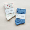 White socks with red polka dots and blue socks with navy polka dots on a grey background.