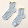 Pair of light blue socks with yellow ruffle edge on a beige background