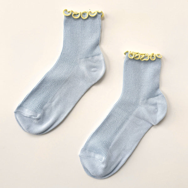 Pair of light blue socks with yellow ruffle edge on a beige background