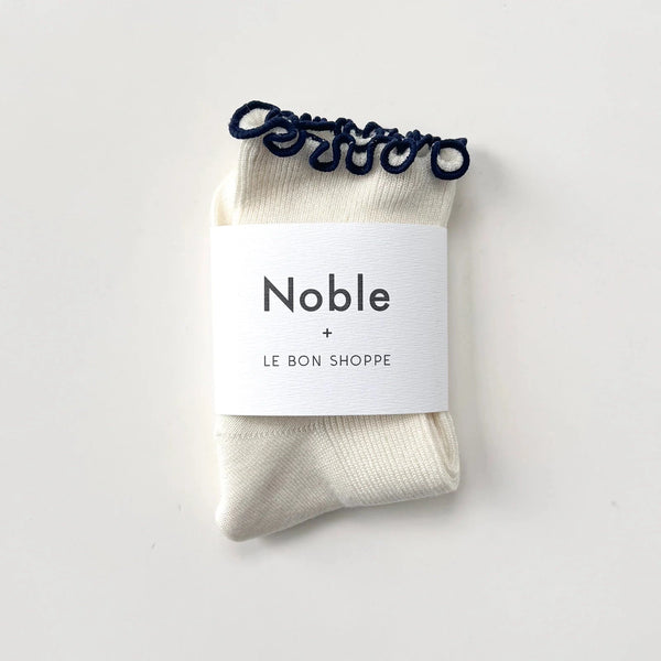 White socks with navy ruffle edge in white paper branded packaging.