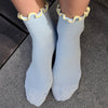 Light blue socks with ruffle yellow trim worn on a dark surface