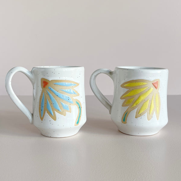 Two ceramic mugs with floral designs on a plain background