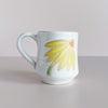 White ceramic mug with yellow coneflower design. 
