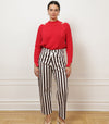 Woman wearing brown and white striped trousers against a white wall. 