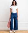 Person wearing dark blue wide leg pants against a white wall.