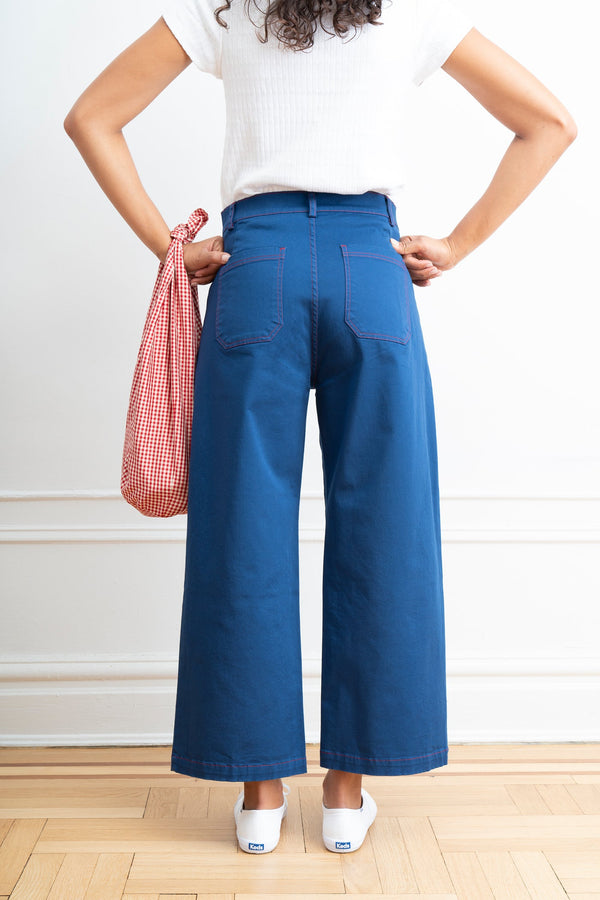 Person wearing blue wide-leg jeans and a white top, holding a red and white checkered bag.
