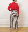 Person wearing brown and white striped trousers facing a white wall.