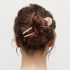 Back view of a person with a stylish hair bun using hair pin on a plain background