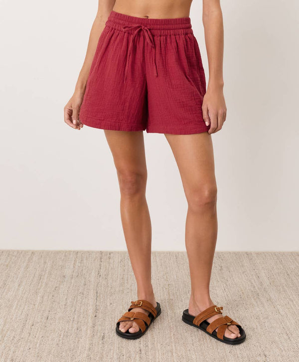 Person wearing red shorts and brown sandals on a neutral background