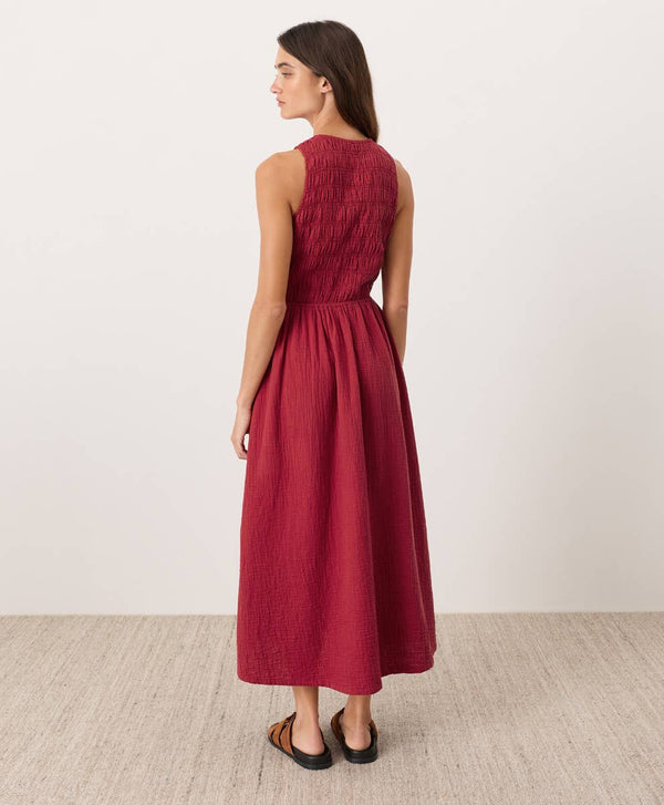 Woman wearing a red sleeveless midi dress standing against a white background