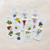 An assortment of pressed floral bookmarks in their packaging on a beige background.