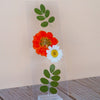 Pressed floral bookmark in a stand against a beige wall. 