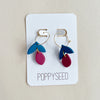 Pair of clay and gold hoop earrings on a 'Poppyseed' branded card against a beige background