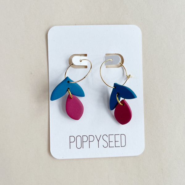Pair of clay and gold hoop earrings on a 'Poppyseed' branded card against a beige background
