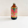 Bottle of Hibiscus Cardamom syrup with a colorful label on a white background
