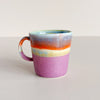 Multicolor glazed ceramic double espresso cup on neutral background.