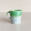 Green and speckled grey gradient glazed ceramic double espresso cup on neutral background.