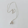 Silver necklace with a bell flower charm pendant on a light gray background