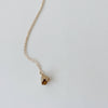Gold necklace with a small yellow bronze bell flower pendant on a light gray background