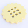 Yellow ceramic flower frog with multiple holes on a white background