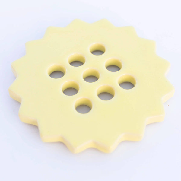 Yellow ceramic flower frog with multiple holes on a white background
