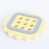 Yellow ceramic flower frog with a gray rubber bumper on a white background