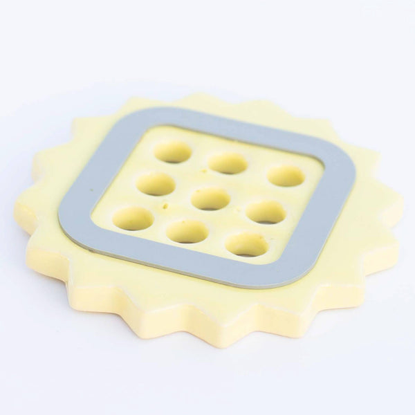 Yellow ceramic flower frog with a gray rubber bumper on a white background