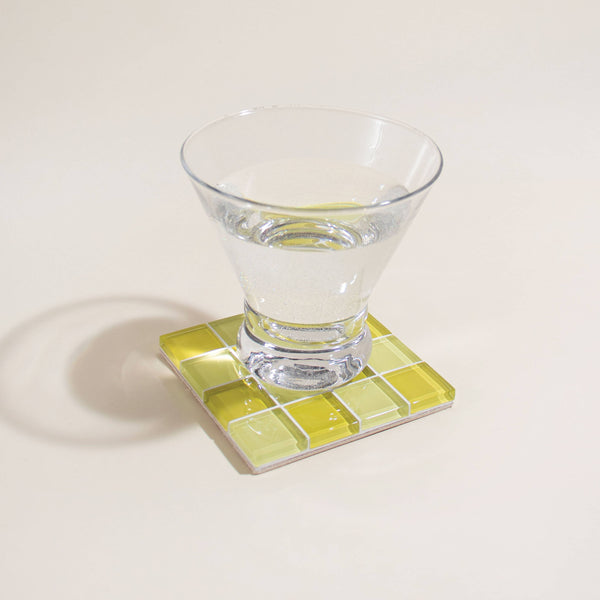 Clear glass on a yellow mosaic coaster with a white background