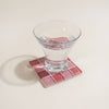 Clear glass on a pink mosaic coaster with a white background