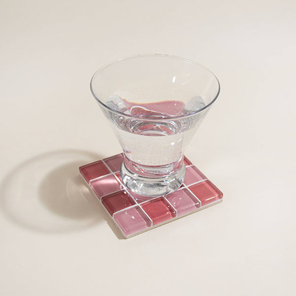 Clear glass on a pink mosaic coaster with a white background
