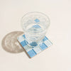 Clear glass with water on a blue mosaic coaster on a light beige surface