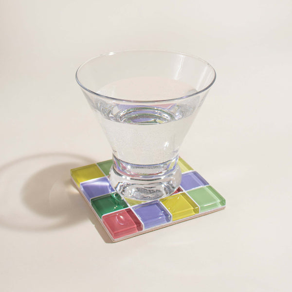 Clear glass on a colorful square coaster with a white background
