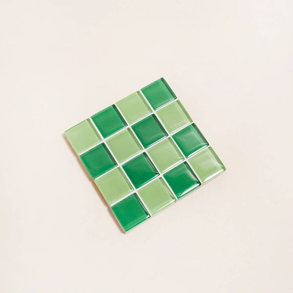 Square glass tile with green square pattern on a beige background