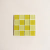 Square tile with two toned yellow grid pattern on a beige background