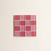 Rectangular glass tile with red and pink checkered pattern on a beige background